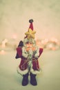 Santa Claus toy brings Christmas tree at blue snowy night bokeh background and blurred lights foreground. Royalty Free Stock Photo