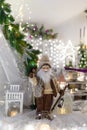 Santa Claus toy in brown clothes standing at white lantern. Fir tree branches and Christmas decorations on blurry background Royalty Free Stock Photo