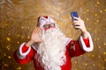 Santa claus using mobile phone during christmas time takes selfie or Royalty Free Stock Photo