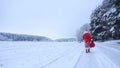 Santa Claus walking on a road in a winter forest