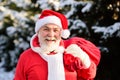 Santa Claus walking to the winter forest with a bag of gifts. Wish Happy New Year. Royalty Free Stock Photo