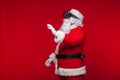 Santa Claus wearing virtual reality goggles, on a red background. Christmas