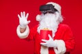 Santa Claus wearing virtual reality goggles and a red bucket with popcorn, on a red background. Christmas