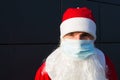 Santa Claus with white beard in red coat in a medical mask. Christmas in the coronavirus pandemic, seasonal diseases, SARS and