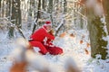 Santa Claus in winter forest with a bag of gifts read wish list on snow landscape. Royalty Free Stock Photo