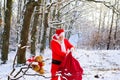 Santa Claus in the winter mountains snow with Christmas present. Santa Claus with gift against winter village. Postcard