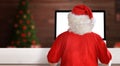 Santa Claus work on computer in his workroom. View from back Royalty Free Stock Photo