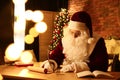 Santa Claus writing letter at table indoors