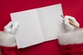 Santa Claus writing a naughty or nice list in a book. blank page mock up Royalty Free Stock Photo