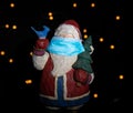 Santa Clause figurine wearing a mouth protection as symbol for impact of Covid-19 virus to Christmas celebration 2020