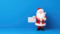 Santa Clause presenting a gift card plain blue backgrouund - stock picture