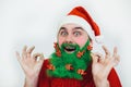 Santa Clause in red clothes with green beard smiles