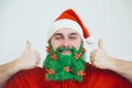 Santa Clause in red clothes with green beard smiles