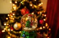 A santa clause in a transparent round glass with snowfall against out of focus christmas tree lights, xmas festive celebration Royalty Free Stock Photo