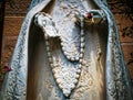 Santa Fe USA - closeup of marble statue of mary with elegant robe and rosary beads. Cropped without head. Someone has