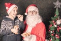 Santa and funny boy with cookies and milk at Christmas