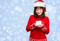 Santa Girl Holding Christmas Gift Over Holidays Lights Background. Young Happy Woman In Santa Hat Showing Christmas Present. Beau