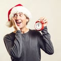 Santa guy holding red clock, isolated on white. Worried man wearing Santa Claus helper hat. Time is coming. New Year and Christmas Royalty Free Stock Photo