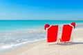 Santa hat on chaise longues at white sand beach against the sea Royalty Free Stock Photo