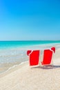 Santa hat on chaise longues at white sand beach against the sea Royalty Free Stock Photo