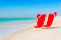 Santa hat on chaise longues at white sand beach against the sea