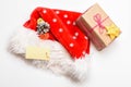 Santa hat with christmas gift box. Keep family traditions. Santa red hat white background top view. Christmas presents