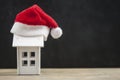 Santa hat with miniature house model over blank chalkboard Royalty Free Stock Photo