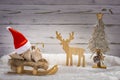 Santa hat with sledge and gifts, a reindeer and Christmas tree in the snow Royalty Free Stock Photo