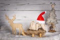 Santa hat with sledge, reindeer and gifts with Christmas tree in the snow Royalty Free Stock Photo