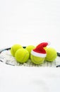 Santa hat on tennis ball, set of tennis balls on racket on white snow winter background. Merry Christmas and New year concept with Royalty Free Stock Photo