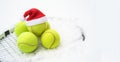 Santa hat on tennis ball, set of tennis balls on racket on white snow winter background. Merry Christmas and New year concept with Royalty Free Stock Photo