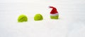 Santa hat on tennis ball on white snow background. Christmas and New year concept with tennis balls. Close up, sport lifestyle Royalty Free Stock Photo