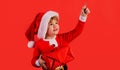Santa helper. Little child boy in Christmas hat with present gift box pointing at copy space. Royalty Free Stock Photo