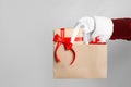 Santa holding paper bag with gift boxes on light grey background, closeup Royalty Free Stock Photo