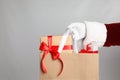 Santa holding paper bag with gift boxes on light grey background, closeup Royalty Free Stock Photo