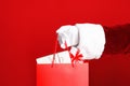 Santa holding paper bag with gift boxes on red background, closeup Royalty Free Stock Photo