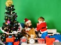 Santa and little assistant among gift boxes near Christmas tree. Royalty Free Stock Photo