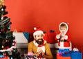 Santa and little assistant among gift boxes near fir tree Royalty Free Stock Photo