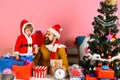 Santa and little assistant among gift boxes near fir tree. Royalty Free Stock Photo