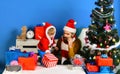 Santa and little assistant among gift boxes near fir tree. Royalty Free Stock Photo