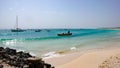 African fishermen launching small wooden skiff from a tropical beach on Cape Verde Islands