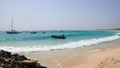 African fishermen launching small wooden skiff from a tropical beach on Cape Verde Islands