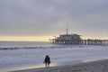 Santa Monica pier in the evening, a couple standing at the beach, seabirds flying in the sky, sea buoys in the pacific, the last Royalty Free Stock Photo