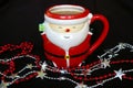 Santa mug with hot drink and shiny string beads in front of it