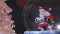 Santa near a beautiful, colourful, New Year`s fir-tree, sits in a glass sphere and prepares gifts for children for new year