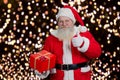 Santa with present giving thumb up. Royalty Free Stock Photo