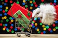 Santa pushing shopping cart of wrapped big screen TVs against bokeh