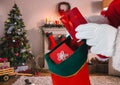 Santa putting gifts in christmas stocking in living room Royalty Free Stock Photo