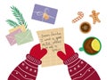 Santa\'s hands are at the table, holding a letter asking for a gift. Table with letters, cookies and gift, top view