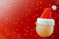 Santa's hat is worn on a gold, Christmas ball toy. Red background, falling snowflakes. 3D rendering